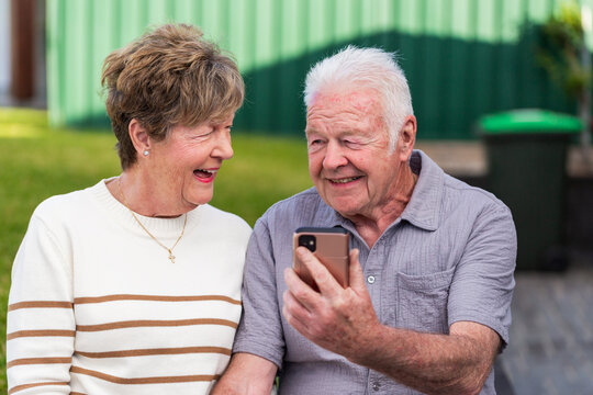 mobile phone device held in hand of senior couple as they smile at photos of grandchildren