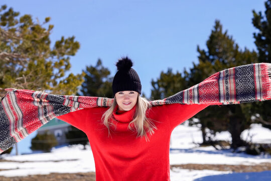 Stylish caucasian woman with spread scarf radiates happiness in snowy forest scene