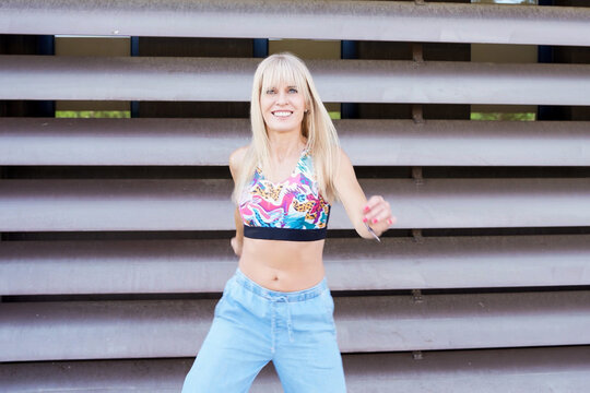 Young woman dancing outdoors in a colorful crop top and jeans