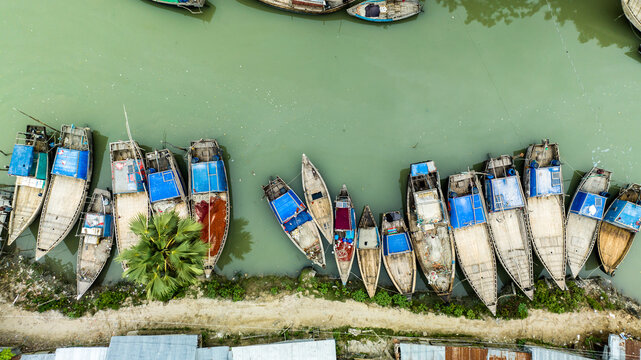 Aerial view of traditional wooden fishing boats moored along the riverbank in Patharghata, Barisal Division, Bangladesh.