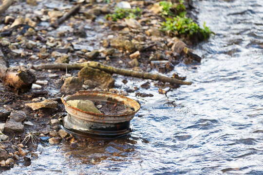 Rusted car rim abandoned on a riverbank