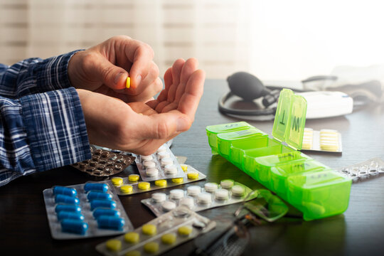 Middle aged caucasian man counts out pills for distributing scheduled dose of medication into pillbox