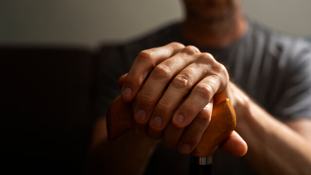 Middle age caucasian man hands holds cane closeup