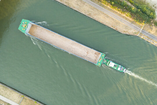 Aerial view of a cargo barge navigating the canal at Haven Genk with calm water and green banks Genk, Vlaanderen, Belgium.