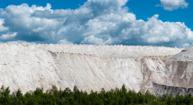 Huge white industrial hills under dramatic summer clouds in Lithuania