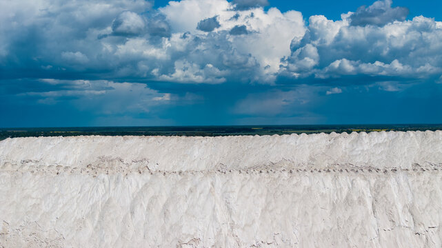 Huge white industrial hills under dramatic summer clouds in Lithuania