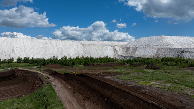 Huge white industrial hills under dramatic summer clouds in Lithuania