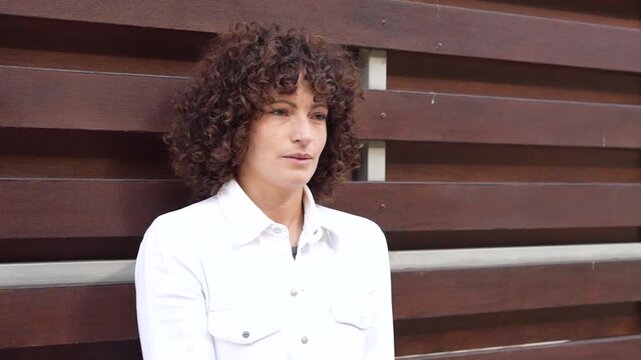 A beautiful portrait of a woman with curly hair set against a rustic wooden background