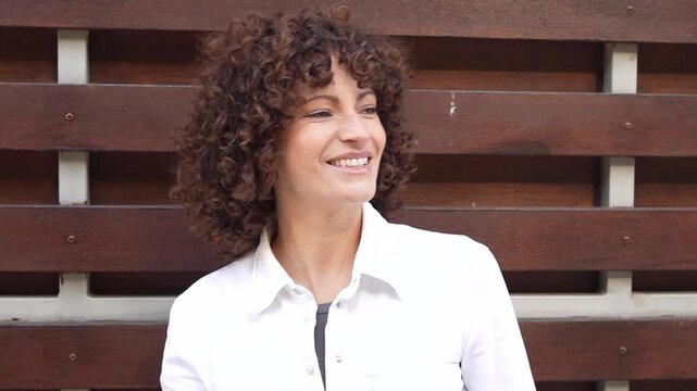 A Beautiful Portrait of a Confident Woman Featuring Curly Hair Set Against a Wooden Background
