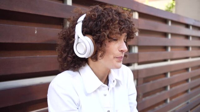 A Joyful Woman Dancing in an Outdoor Setting While Wearing Headphones and Embracing Life