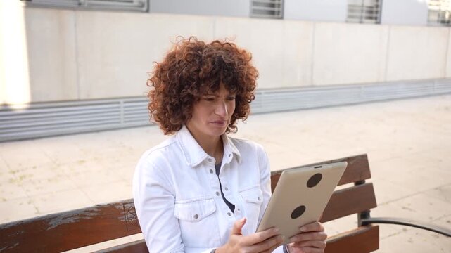 A Woman Engaged in a Video Call While Seated Outdoors with Her Tablet on a Beautiful Day