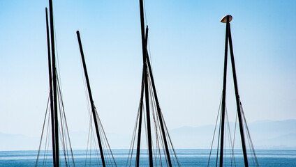 Mástiles de varios veleros recortados contra el horizonte marino. Las líneas verticales y diagonales de los cables crean una composición minimalista y geométrica. © Menorcaevo
