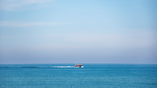 Barco solitario surcando mar azul.