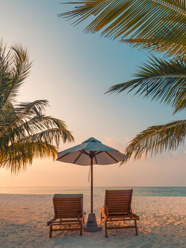 Romantic sunset tropical beach two loungers umbrella palm trees calm sea sandy shore glowing evening paradise. Perfect summer vacation travel scene. Luxury honeymoon couples relax love coastal getaway