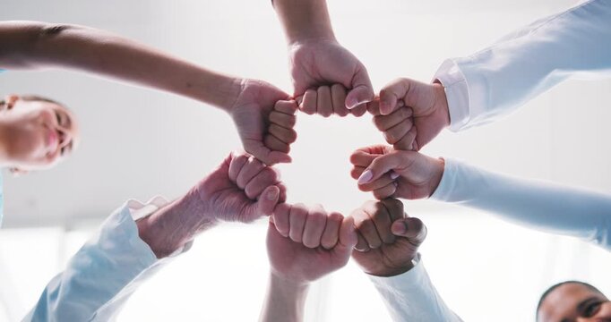 Doctor, unity and medical team with fist bump for collaboration, agreement or partnership. Low angle, people or healthcare community with hands together for solidarity, mission or support in hospital