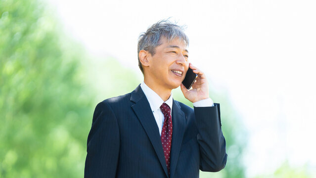 スマートフォンで通話するシニア男性ビジネスマン