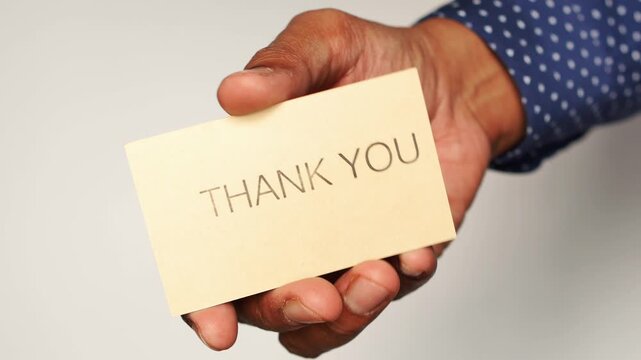 Hand extends small thank you card in offering gesture over white background with subtle motion