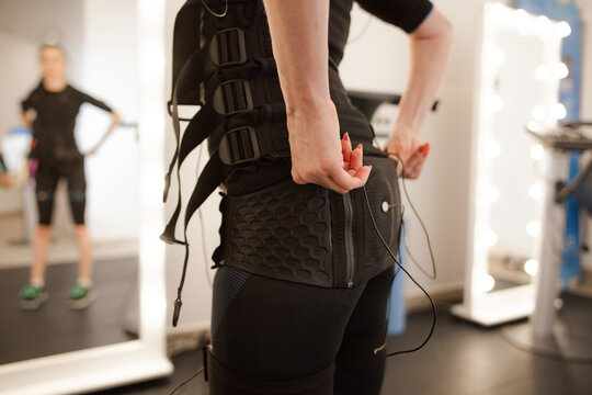 woman hands wearing EMS suit for electrical muscle stimulation workout in fitness studio