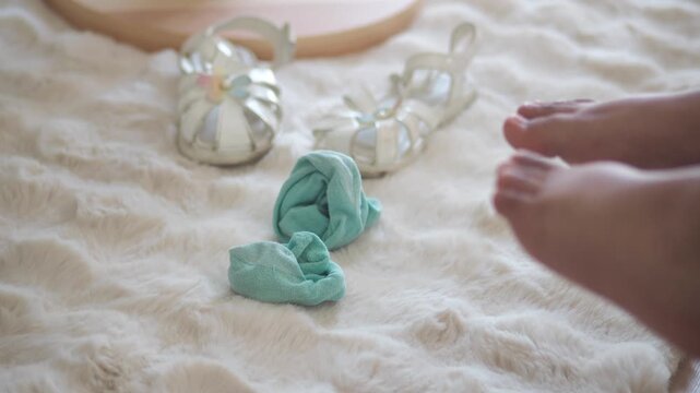 Close up on childs feet and baby sandals with socks on furry rug