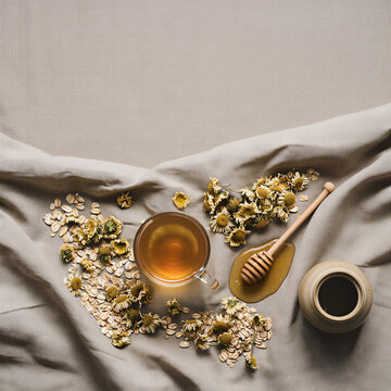 Chamomile tea with honey dipper on linen flat lay