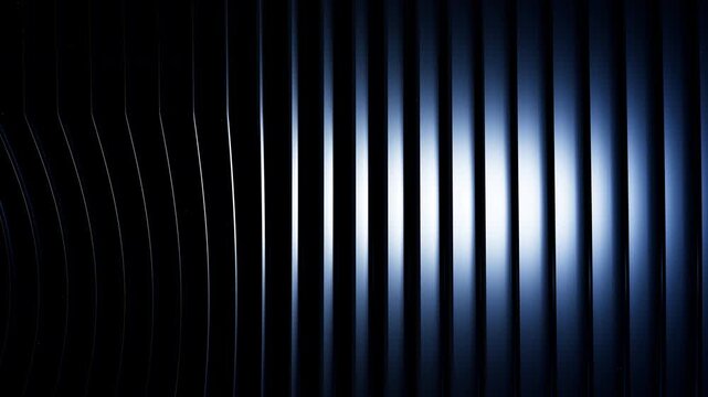 Waving metallic fluted architectural louvers reflecting light creating a navy blue abstract background