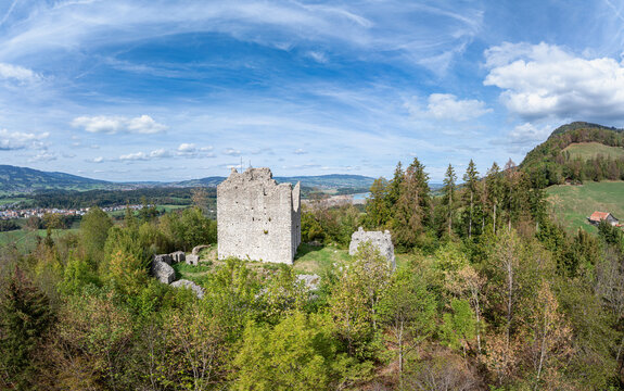 Aerial view of the historic ruins of Burg Montsalvens surrounded by lush green forests and rolling hills in Broc, Fribourg, Switzerland.