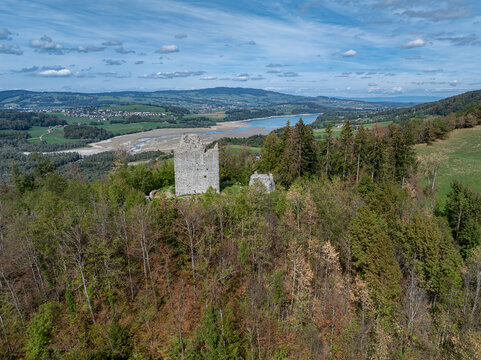 Aerial view of the historic ruins of Burg Montsalvens surrounded by dense forest, overlooking the scenic landscape and lake near Broc, Fribourg, Switzerland.
