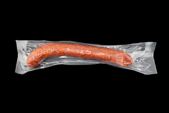 Sausages in vacuum plastic packaging isolated on black background. Vacuum transparent packaging with fresh sausages. A pack of sausages in a vacuum isolated.