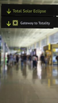 Airport sign indicating the direction for the total solar eclipse event, with travelers walking in a blurred background, representing the concept of astro tourism and celestial event travel