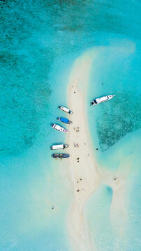 Aerial view of Sandbanks Beach with several boats moored on the white sand surrounded by turquoise water in Raja Ampat, Southwest Papua, Indonesia.