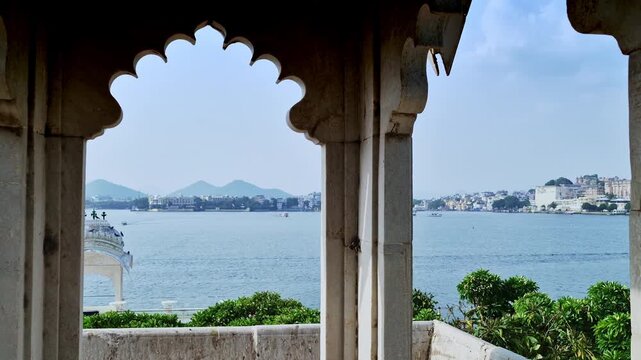 Lake Pichola and the far shore appear through a row of shaded scalloped arches at Jag Mandir in Udaipur.