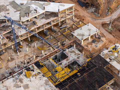 Aerial view of a large construction site featuring concrete building frames, steel reinforcement bars, and a blue tower crane in Santo Domingo Este, Santo Domingo Provinc, Dominican Republic.