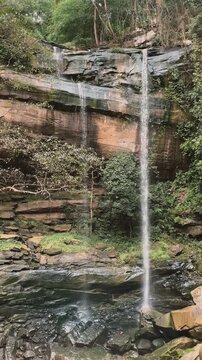Serene Natural Waterfall Flowing Over Layered Rocks in a Vibrant Thai Jungle Landscape