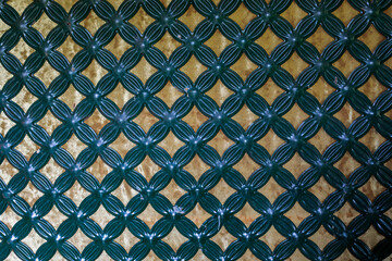 Teal and gold geometric pattern background with interlocking circles and diamond shapes, ornamental metalwork texture captured closeup with vibrant rich contrasting colors, high quality photo © Татьяна Швец
