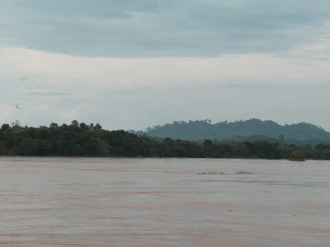 Thailand's natural landscape: wide river, dense tropical forests, distant mountains, cloudy sky.