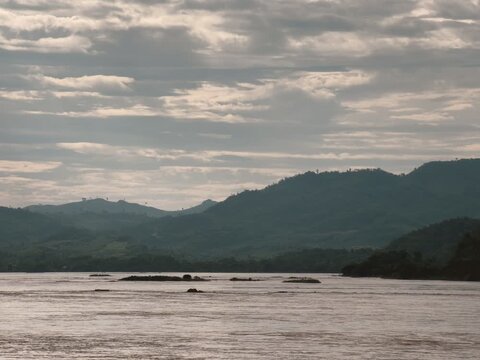 Mekong River Landscape with Lush Green Mountains Under a Cloudy Sky in Southeast Asia