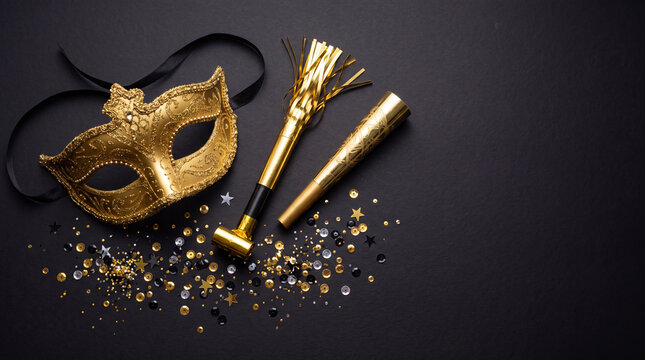 Golden carnival mask with party blowers and sequins on dark surface