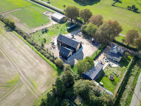 Interesting drone view of a newly completed, modern detached family home in rural Britain. Seen adjacent to a horse paddock and a more traditional detached home in East Anglia.