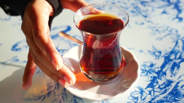 A cup of tea close up shot in motion, picking up beverage from table with hand.
