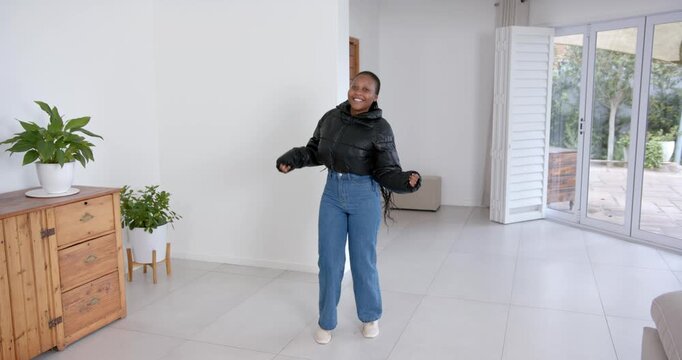 High speed photography for dynamic scenes, smiling woman in black jacket dancing in modern living ro