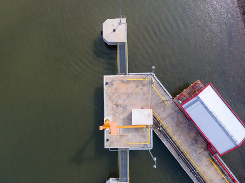 Aerial view of Sleko Harbor with its concrete pier, industrial structures, and a small crane extending into the water in Cilacap, Central Java, Indonesia.