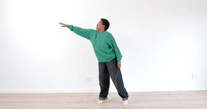 African American man balancing on one leg, extending arm forward in dynamic pose