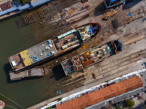 Aerial view of Sleko Port with cargo ships docked in the harbor, showing industrial infrastructure and surrounding buildings in Cilacap, Central Java, Indonesia.