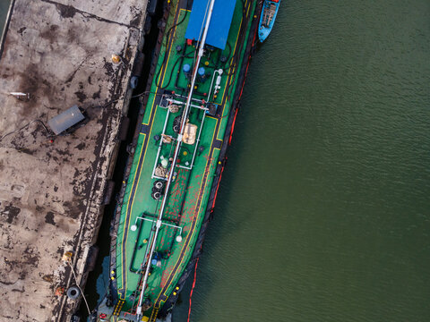 Aerial view of a cargo ship docked at the Port of Tanjung Intan Cilacap, featuring its green deck and industrial equipment alongside the concrete pier in Cilacap, Central Java, Indonesia.