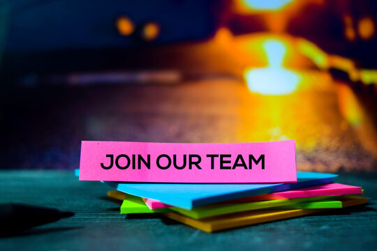 Pink sticky note with join our team text on a stack of colorful sticky notes