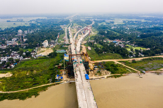 Aerial view of the Padma Bridge under construction spanning the river with surrounding green landscape and rural infrastructure in Mawa, Dhaka Division, Bangladesh.