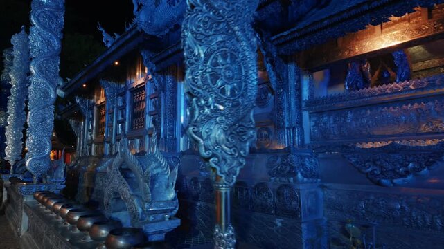 silver temple Wat Sri Suphan illuminated with blue light at night, ornate carved metal architecture facade in Thai shrine landmark at Chiang Mai 4k