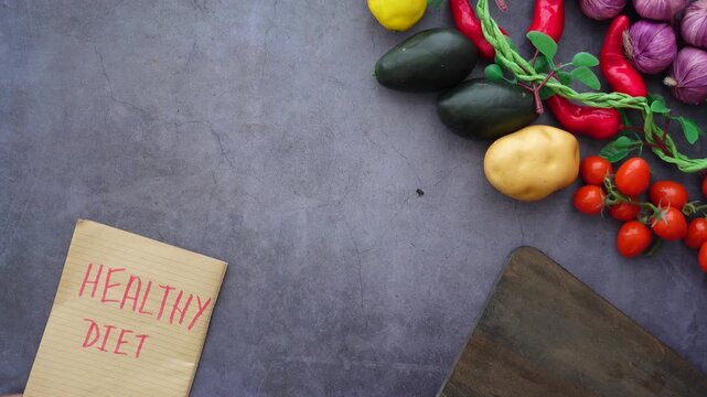 Top view of healthy diet note surrounded by fresh vegetables and fruits on table.