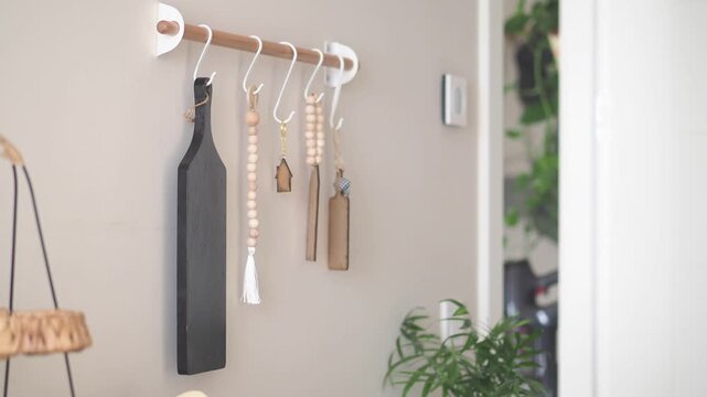 Scandinavian kitchen storage rack with decorative cutting boards and wooden beads hanging.