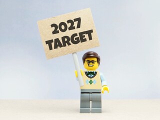Obraz premium Indonesia - June 12, 2026 : Mini toy of action figure at table with blurred background. Business Miniature photography concept design. Minifigure of people with 2027 PLAN text at paper poster banner.